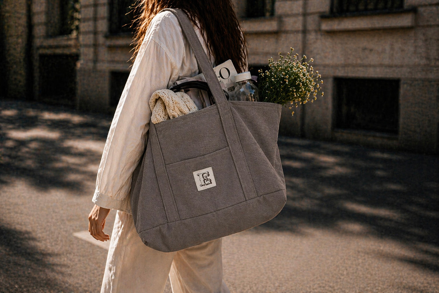 All-In bag on a model, filled with daily objects like water bottle and magazine, by Esra Kayira. 