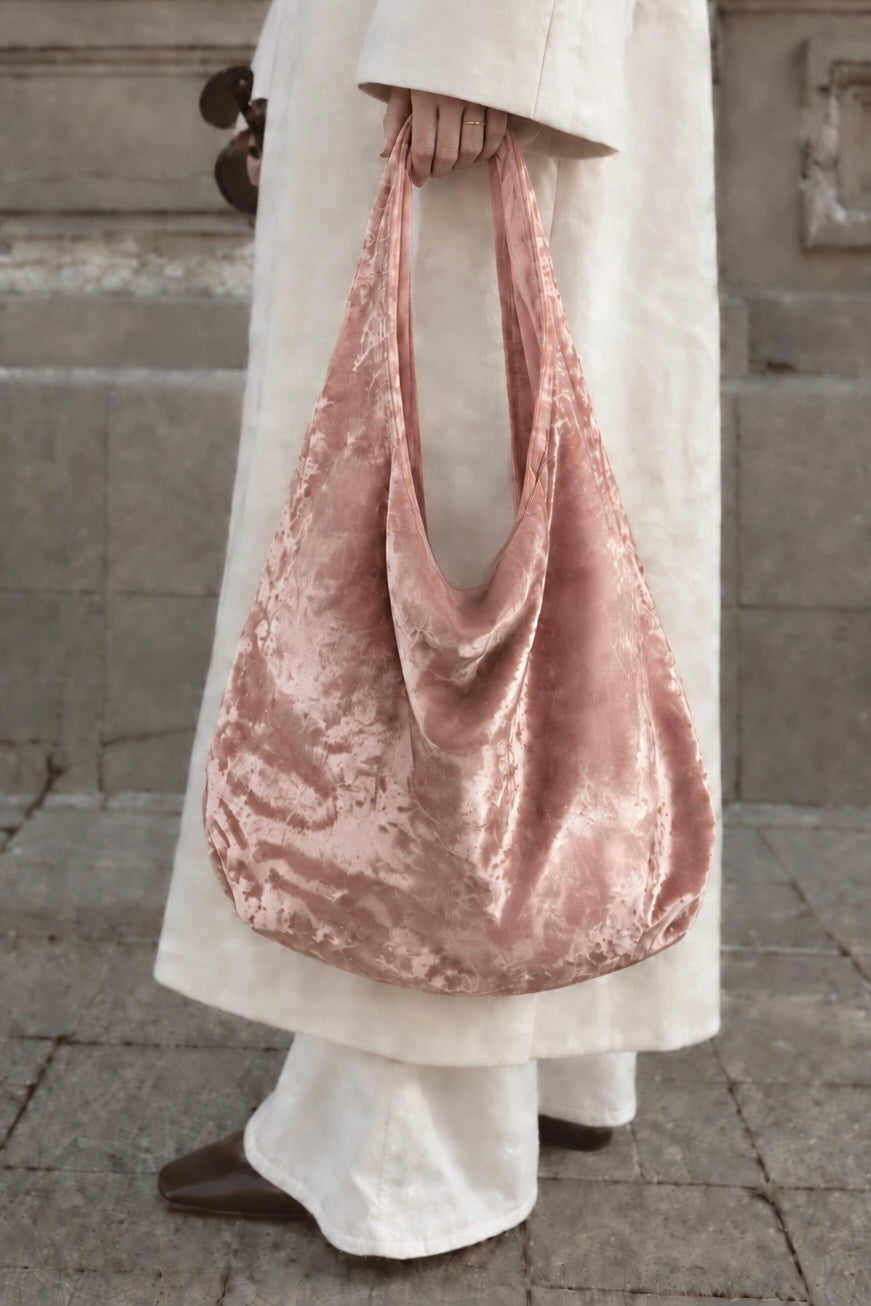 Model holding the blush pink crushed velvet bag, by Esra Kayira.