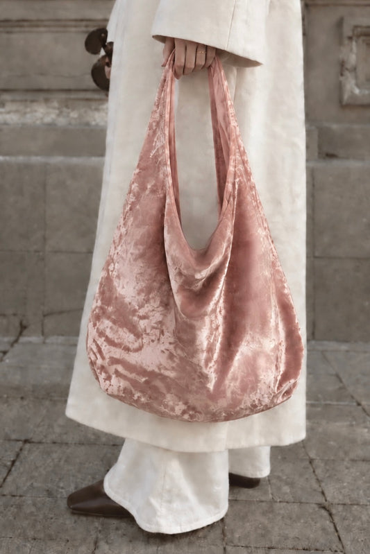 Model holding the blush pink crushed velvet bag, by Esra Kayira.