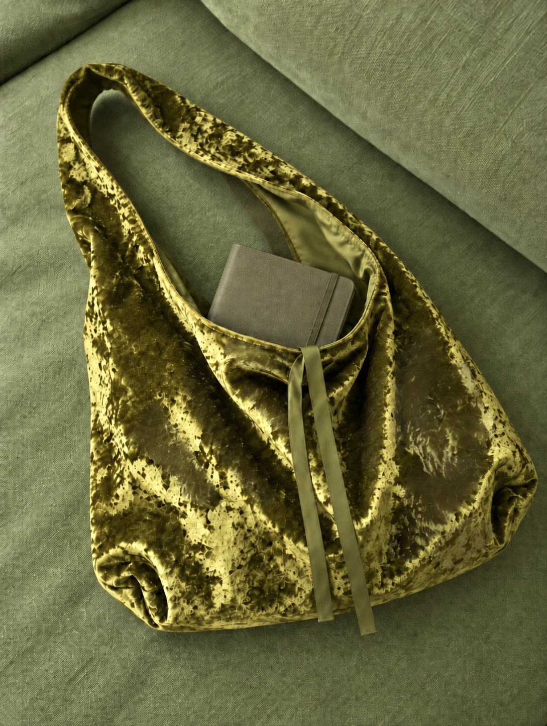 Golden olive green crushed velvet bag on a green couch,  by Esra Kayira brand.