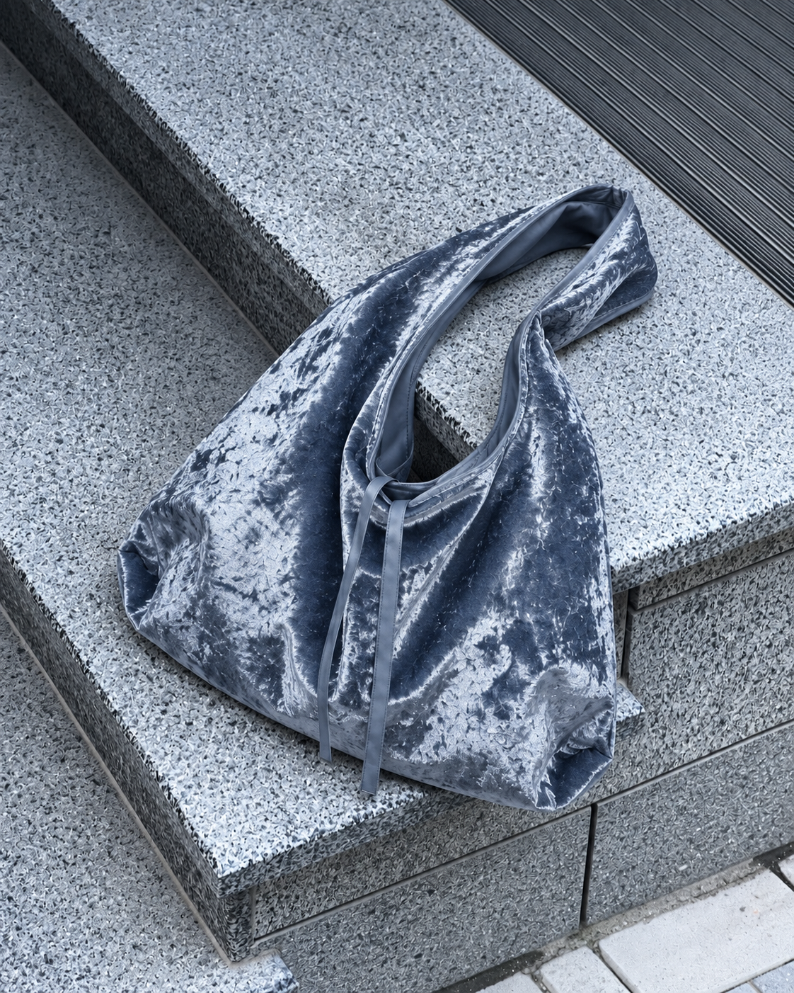 Silver blue crushed velvet bag concrete stairs, by Esra Kayira.